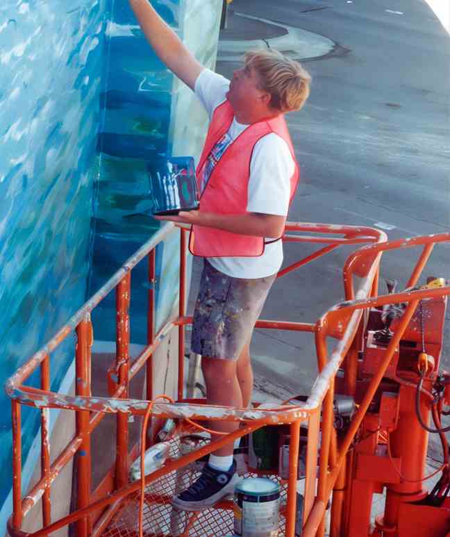 Tom Taylor owner of Berkeley Signs & Banners painting an outdoor sign in Berkeley, CA
