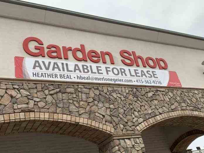 Storefront of a building with a large red 'Garden Shop' sign and a banner below it that reads 'Available for Lease' with contact information.