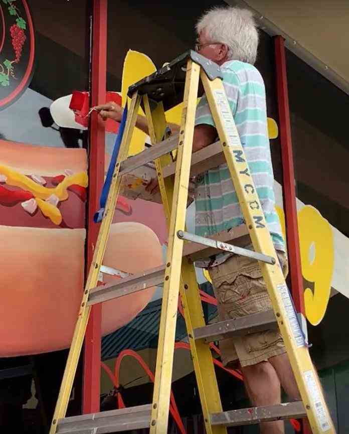 Tim Taylor hand-painting window graphics on a storefront