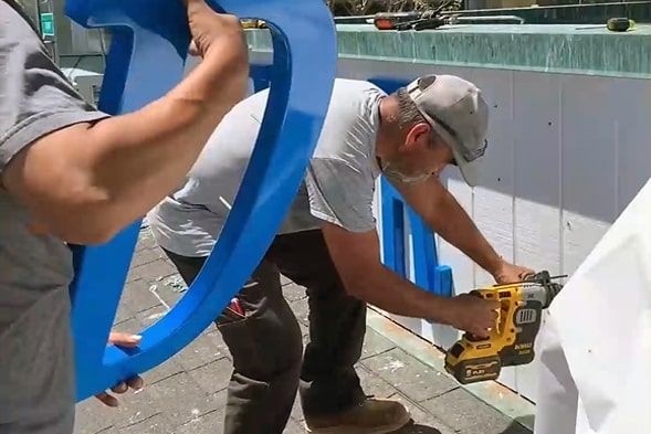 Technician installing exterior wall sign on a San Francisco building