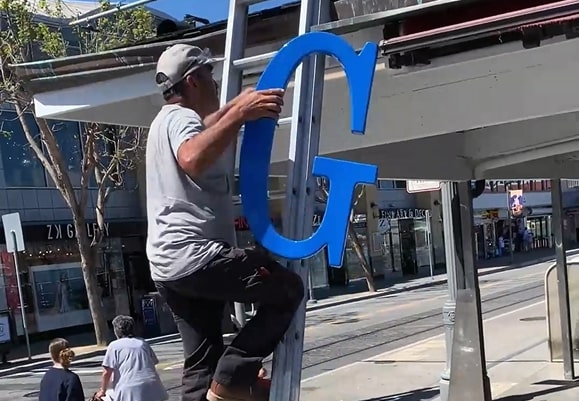 Installer mounting sign at Fisherman’s Wharf restaurant in San Francisco
