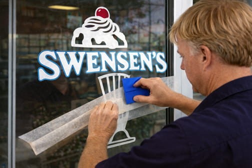Installer applying cut vinyl graphics to a storefront window